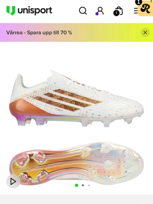 Adidas vita fotbollsskor med koppar - Snygga fotbollsskor från Adidas i vitt med kopparfärgade detaljer och skimrande sula. Skorna har klassiska tre ränder på sidan, låg profil och snörning. Ovandelen är i syntetmaterial med små mönster och textur för bättre bollkontroll. Perfekta för spel på gräs. Använda en gång ändast!
