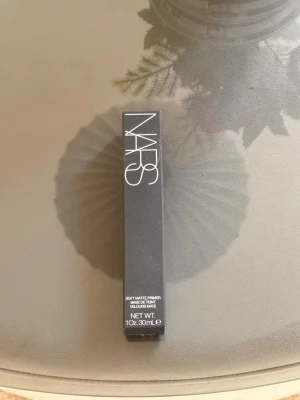 NARS Soft Matte Primer  - NARS Soft Matte Primer i svart förpackning med vit text. Primern ger en matt finish och kommer i en smidig tub på 30 ml. Perfekt för att skapa en jämn bas innan foundation. Snygg och stilren design som känns lyxig. Den är helt oöppnad och oanvänd. 