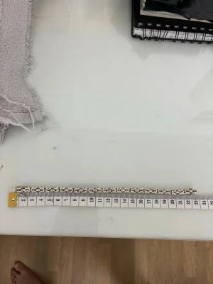 Silvrigt flätat armband - Snyggt armband i silverfärg med flätad design och geometriskt mönster. Armbandet är cirka 21 cm långt och har en stilren look som passar till många outfits. Perfekt accessoar för dig som gillar detaljer och enkel elegans.