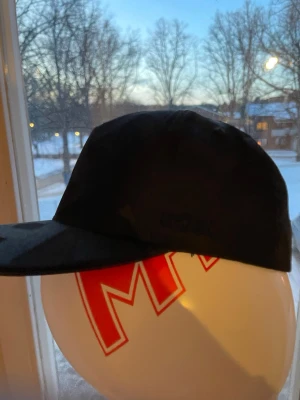 Svart keps med rak skärm - Säljer en stilren svart keps med rak skärm och låg profil. Kepsen har minimalistisk design utan synliga loggor eller detaljer och passar perfekt till streetwear eller casual outfits. Materialet ser ut att vara bomull eller polyester.