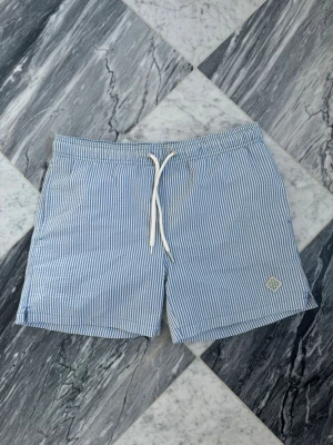Blårandiga badbyxor  - Säljer ett par stilrena badbyxor från gant med tunna blå och vita ränder samt vit dragsko i midjan. Klassisk passform och kortare ben. Liten logotyp på vänster ben. Perfekta för stranden eller poolen.