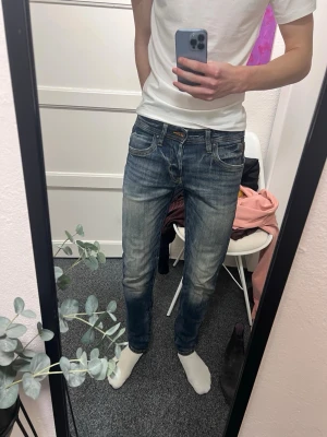 Rare jacknjones jeans - Säljer ett par blå slim fit jeans med snygga slitningar och tvättade detaljer. Jeansen har klassisk femficksmodell, låg midja och smal passform. Perfekta till vardagslooken och passar till det mesta. Materialet är denim i bomull.