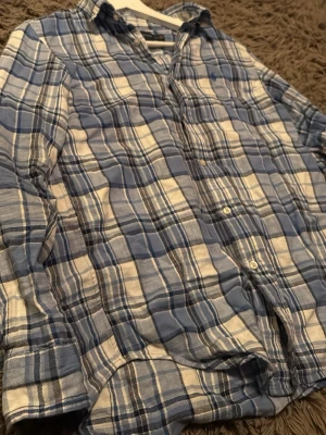 Blårutig skjorta från polo Ralph lauren - Säljer en snygg blårutig skjorta från polo Ralph lauren. Skjortan har klassisk krage, långa ärmar och knäppning framtill. Materialet är mjukt och bekvämt, perfekt för en avslappnad look. Diskret logga broderad på bröstet. Skjortan är skrynklig men ger man den en strykning är den vid fullt liv igen🤗😂