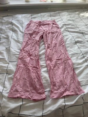 Rosa loungebyxor med resårmidja - Mysiga rosa loungebyxor i mjukt bomullsmaterial med resår i midjan och avslappnad passform. Perfekta för chill hemma eller som sovplagg. Byxorna har raka ben och enkel design utan fickor.