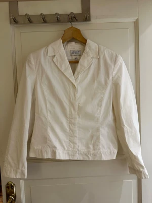 Vit kavaj från Apart Impressions - Vit kavaj från Apart med klassisk krage och knäppning framtill. Översta knappen synlig , övriga dolda. Kort i modellen . 