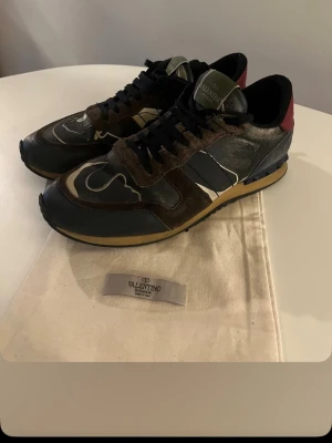 Valentino rockrunners - Snygga sneakers från Valentino Garavani i svart mocka och läder med detaljer i vitt och vinrött. Skorna har svarta snören, beige sula och coola nitar på hälen. 