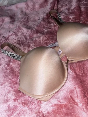 Beige push-up bh från Victoria's Secret - Snygg beige push-up bh från Victoria's Secret med vadderade kupor och glittriga axelband där märkesnamnet står i stenar. Bh:n har slät yta och ger ett lyft. Perfekt för dig som vill ha något extra till din underklädesgarderob. Nypris ca 800kr mitt pris 450kr ( pris går att diskutera) storlek 36DD. Använd 2-4 gånger men tyvärr lite för stor, annars helt ny. 