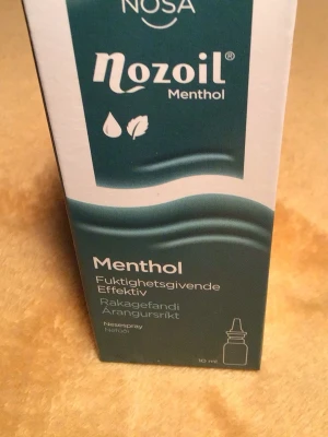 Nozoil Menthol nässpray 10 ml - Nozoil Menthol nässpray med fuktgivande effekt, innehåller menthol och sesamolja. För torrt klimat, förkylning eller vid användning av vissa mediciner. Förpackningen är grön och vit och rymmer 10 ml.