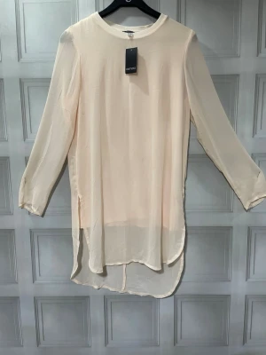 Ljusbeige långärmad blus Esmara - Stilren och luftig ljusbeige blus från Esmara. Blusen har rund halsringning, lång ärm och är tillverkad i ett tunt, transparent material som ger en flowy känsla. Perfekt att styla med jeans eller kjol för en trendig look.