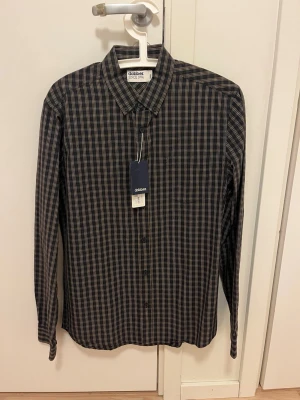 NY oanvänd skjorta från Dobber - Klassisk långärmad skjorta från Dobber i rutigt mönster. NY och oanvänd med etiketter kvar. Storlek small.