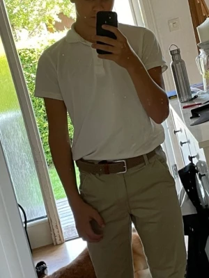 Vit klassisk pikétröja - Säljer en stilren vit pikétröja med krage och knappar framtill. Tröjan har korta ärmar och är tillverkad i mjukt bomullsmaterial. Perfekt för en clean och enkel look.