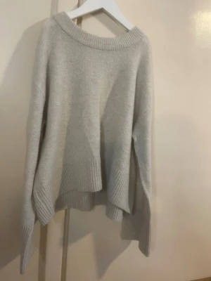 Ljusgrå oversized stickad tröja - Mysig ljusgrå stickad tröja från gina tricot med oversized passform och bred ribbad kant vid hals, ärmslut och nederkant. Tröjan har långa ärmar och är tillverkad i ett mjukt material som passar perfekt för kyliga dagar, och som något till vardagen