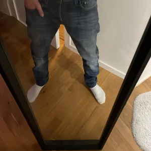 Blå raka jeans med tvättade detaljer - Säljer ett par blå jeans med raka ben och snygga tvättade detaljer. Jeansen har klassisk femficksmodell och normal midja. Perfekta för dig som gillar en avslappnad men ändå stilren look.