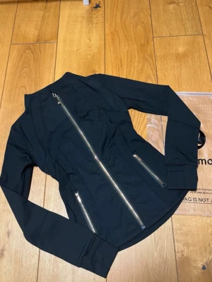 Lululemon jacka  - Snygg svart Define träningsjacka från Lululemon med figurnära passform. Jackan har tvåvägsdragkedja framtill, två dragkedjeförsedda fickor och tumhål vid ärmsluten. Tillverkad i ett stretchigt, fukttransporterande material som andas.