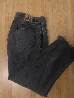Svarta raka jeans från sweet SKTBS  - Säljer ett par svarta raka jeans från sweet sktbs med klassisk femficksdesign och råa, avklippta benslut. Jeansen har en vintage look och är tillverkade i kraftig denim. Perfekta för dig som gillar en avslappnad och trendig stil.