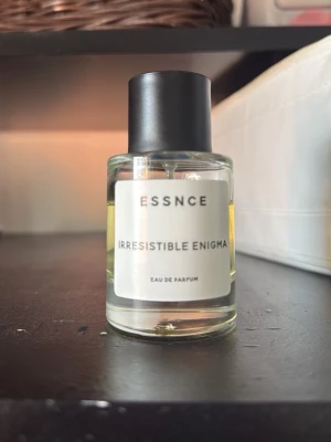 ESSNCE Irresistible Enigma parfym -  parfymflaska från ESSNCE med doften Irresistible Enigma. Härlig parfym som funkar att bygga på med andra parfymer  75-80% kvar i flaskan. Som ny innehåller parfymen 50 ml 