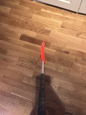 Vit Innebandyklubba med orange blad och grå Linda  - Säljer en innebandyklubba med svart grepp, vitt skaft och ett böjt orange blad. Perfekt för dig som gillar att spela innebandy och vill ha bra kontroll på bollen. Klubban är lätt och smidig att hantera, och bladet är gjort i slitstark plast.