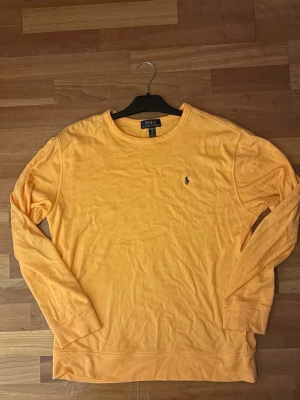 Aprikos tröja Polo Ralph Lauren - Snygg  långärmad tröja från Polo Ralph Lauren med rund halsringning och den klassiska lilla broderade loggan på bröstet. Tillverkad i mjukt material som känns skönt mot huden. Perfekt för dig som gillar stilrena och tidlösa plagg.