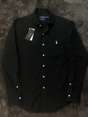 Polo Ralph lauren skjorta - Super snygg svart Ralph lauren skjorta i storlek S, inga defekter. Nypris 1800kr mitt pris endast 650kr, hör gärna av er vid frågor. Mvh Luxury closet🙌😊