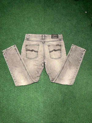 Nudie Jeans - Gråa Nudie Jeans med en riktigt sjysst tvätt, Storlek W30 L28. Jeansen är i riktigt bra skick förutom ett litet hål vid knät men som knappt syns vid användning. Modell Lean dean. Hör av er vid minsta funderingar!