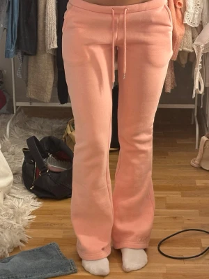 Bootcut mjukisbyxor i korall  - Säljer ett par korall mjukisbyxor med bootcut-modell och dragsko i midjan. Byxorna har en avslappnad passform och är tillverkade i mjukt, fleeceliknande material. Perfekta för chill dagar hemma eller när du vill vara bekväm men ändå se snygg ut.💞💞De är från nitted och är slutsålda där!