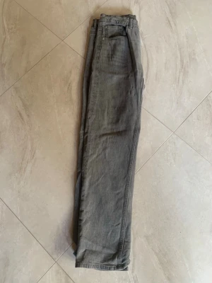 Grå raka jeans från H&M - Säljer ett par grå jeans från lager 157 med rak passform och klassisk femficksdesign. Jeansen har normal midja och är tillverkade i ett mjukt denimtyg. Perfekta för en avslappnad och stilren look.