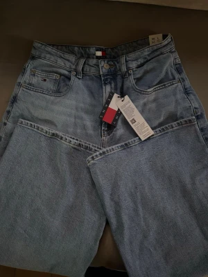 Ljusblå wide leg jeans Tommy Hilfiger - Säljer ett par ljusblå wide leg jeans från Tommy Hilfiger. Jeansen har hög midja och raka, vida ben. Aldrig använd endast testad, alla taggar kvar! 30 midja 30 benlängd. 1,199kr original!