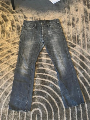Blå raka jeans från Jack n Jones  - Säljer ett par klassiska blå jeans från Jack n Jones med raka ben och slitna detaljer. Jeansen har fem fickor, knappgylf och kontrastsömmar. Materialet är denim i bomull och passformen är avslappnad men ändå snygg.