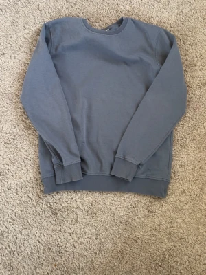 Kappahl sweatshirt herr blå bomull storlek S - KappAhl sweatshirt för herr i storlek S. Tröjan är blå och tillverkad i bomull. Rund halsringning med ribbad mudd vid hals, ärmslut och nederkant. Passar som vardagströja eller som extra lager vid kyligare väder.