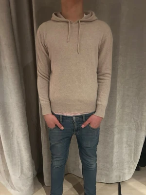 Kashmir hoddie - Säljer en stilren beige hoodie med huva och dragsnören. Hoodien är tillverkad i Kashmir och har ribbade muddar vid ärmar och nederkant. Perfekt för dig som gillar en clean och enkel look. Rikigt fet, säljer billigt men pris kan också diskuteras👍 jag är 173 lång på bilden