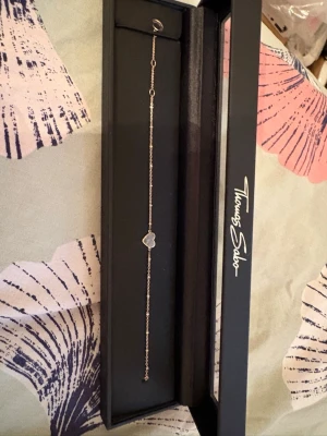 Tunt armband med hjärta Thomas Sabo - Säljer ett elegant och tunt armband från Thomas Sabo i silverfärg. Armbandet har en fin kedja och ett litet hjärta i mitten som detalj. Perfekt för dig som gillar stilrena och minimalistiska smycken. Köptes för 800kr om jag minns rätt. 