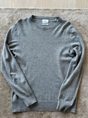 Grå 100% kashmirtröja  - Mjuk och stilren grå tröja i 100% kashmir från Bläck. Den är i storlek M och nypris ligger på 1800kr mittpris 800kr. Den är i bra skick förutom en defekt på en armbåge se bild 6. Bara att skriva vid funderingar mvh Liam.