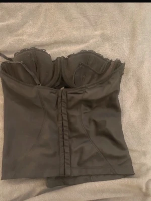 Svart satin korsett med spetsdetaljer - Snygg svart korsett i satin med spetskant upptil framsidan har en satin knyttning står ingen storlek men skulle tippa på s till m💓