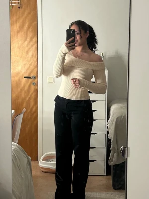 Beige offshoulder ribbad topp - Trendig beige offshoulder topp med ribbad struktur och lång ärm. Sitter tight och framhäver ena axel på ett snyggt sätt. Perfekt för dig som vill ha en stilren men ändå unik look.
