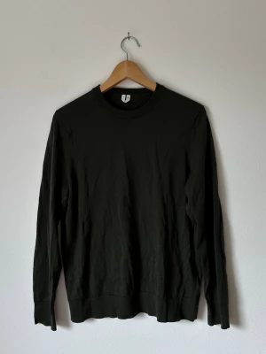 Mörkgrön tröja från Uniqlo - En stilren mörkgrön långärmad tröja från Uniqlo med rund halsringning. Tröjan är tillverkad i ett mjukt och lätt material, perfekt för lager på lager eller som den är. Enkel design utan tryck eller mönster, passar till allt. 6R16