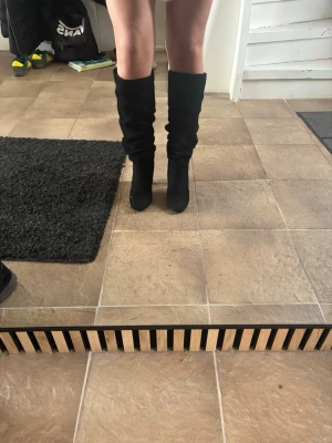 Svart stövlar  - Säljer ett par svarta höga stövlar med slouchy passform och rund tå. Stövlarna har en stilren look och är tillverkade i mockaimitation som ger en mjuk känsla. Perfekta att styla till kjol eller klänning för en trendig outfit. Perfekt nu till våren och sommaren. Passar bra till fest såsom till vardagen💕