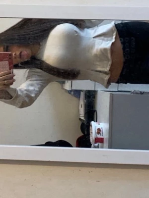 Vit croppad långärmad topp - Snygg vit croppad topp med lång ärm och lätt utsvängda ärmslut. Toppen har en figurnära passform och är tillverkad i ett mjukt material, perfekt för en trendig look.