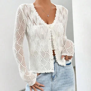 Vit stickad kofta - En ny vit stickad kofta med ett snyggt hålmönster. Koftan har långa ärmar och dekorativa kanter. Perfekt för sommar och ger en luftig känsla.