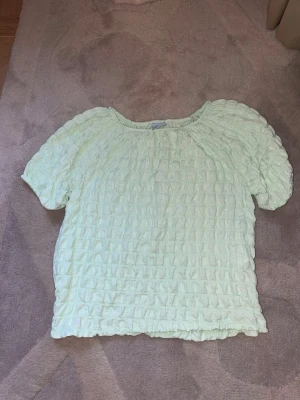 Ljusgrön topp från Zara - Supersöt ljusgrön topp från Zara med korta ärmar och ett strukturerat, ribbat tyg. Toppen har en avslappnad passform och rund halsringning. Perfekt för dig som gillar en enkel men trendig stil. Kan gå ner i pris 