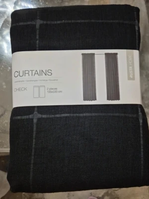 Svarta rutiga gardiner från Rusta - Säljer ett set med två svarta gardinlängder från Rusta Home, modell Check. Gardinerna har ett diskret rutmönster och mäter 135x220 cm. Perfekta för att ge rummet en stilren och modern känsla.