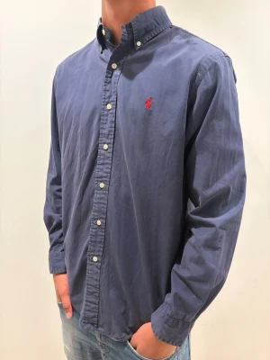 Mörkblå Ralph lauren skjorta - strl M - Ralph Lauren skjorta 👔✨ Mörkblå med röd logga 🔴💙 Storlek M 👀 Snygg passform som funkar både uppklätt och mer avslappnat 😎🔥 Klassisk och tidlös design Kolla in profilen för flera feta Ralph Lauren skjortor 👀🔥 Hör av er om ni har frågor eller vill ha fler bilder 💬