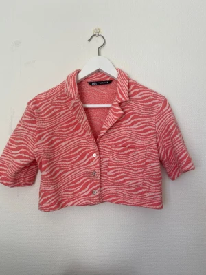 Zara orange/rosa mönstrad topp stl XS – som ny - Jättefin topp från Zara i härlig orange/rosa nyans med mönster. Storlek XS. Använd vid max fem tillfällen och i mycket fint skick, nära nyskick. Lätt och luftig modell som passar perfekt till vår och sommar, både till vardag och fest. Djur- och rökfritt hem.  Material: 100 % polyester.