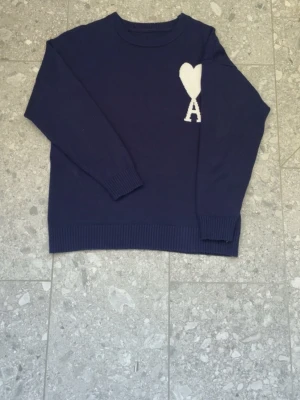Ami Paris  - Ami paris tröja i mörkblå färg med vit loga den är i storlek S men passar som M man behöver va 175-180 för den ska sitta perfekt o slim den har en defekt där bakom axeln men har sytt den 