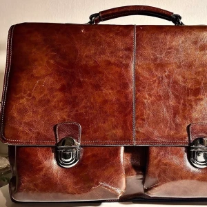 Vintage Puccini läderportfölj – Äkta skinn – Businessmodell - Säljer en riktigt snygg och tidlös portfölj från italienska Puccini. Den är gjord i högkvalitativt, mjukt brunt läder som bara blir snyggare med åren. Perfekt för dig som vill ha en unik väska. 100% äkta läder. Skick: Superfin vintage-condition med naturlig patina som ger karaktär. Inga stora skador, väl omhändertagen. Två stora huvudfack + mindre fickor framtill under locken. Rymmer enkelt en 15" laptop. Stil: Klassisk "old money" / dark academia