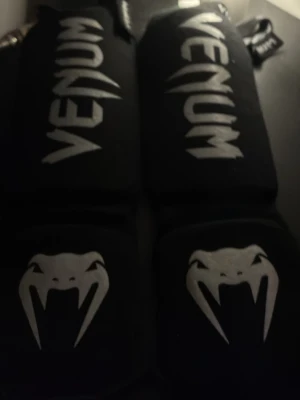 Svarta shinpads från Venum - Säljer ett par svarta benskydd från Venum med vit logga och ormtryck. Perfekt för nybörjare/fortsättning