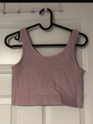 Träningstopp  - Säljer en ribbad träningstopp från Bik Bok. Toppen är ärmlös och har en croppad passform som sitter snyggt på kroppen. Perfekt till både träning och vardag.(ifrån Bikbok) 