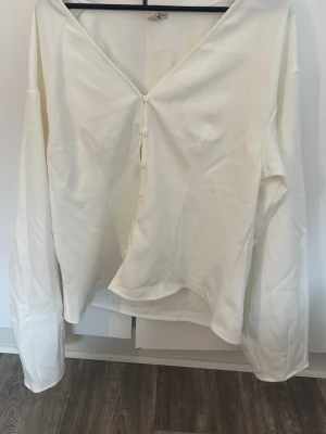 Vit v-ringad blus med knappar - Stilren vit blus från Nelly med v-ringning och knappar framtill. Blusen har lång och puffig ärm.
