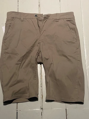 Beige shorts i bomull, storlek M - Snygga beige shorts från UNDERFABRIC i storlek M. Klassisk modell med normal passform, bälteshällor och sidofickor. Tillverkade i mjuk bomull, perfekta för varma dagar. Stängs med knapp och dragkedja framtill. Nypris: 499