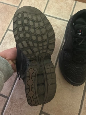 Svarta Nike Shox sneakers - Säljer ett par helsvarta Nike Shox sneakers med klassisk fjädrande sula och mesh-överdel. Skorna har en sportig look med tydliga Shox-detaljer på hälen och snörning framtill. Perfekta för dig som gillar streetwear och vill ha något bekvämt och stilrent.