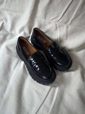 Svarta chunky loafers från NA-KD - Snygga svarta loafers från NA-KD med chunky sula och klassisk pennyloafers-design. Använda 1 gång.